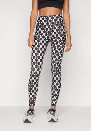 Svartvita mönstrade leggings har en geometrisk design med hexagonala former, ett högt midjeband och en slät, stretchig textur.