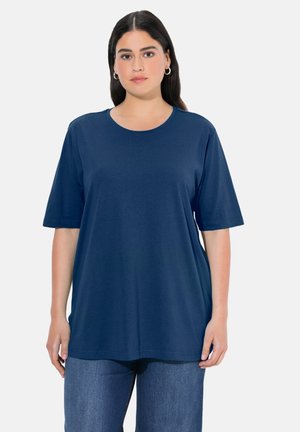 Maglietta a maniche corte blu navy realizzata in tessuto morbido. Caratterizzata da un collo rotondo e una vestibilità ampia, abbinata a jeans in denim.