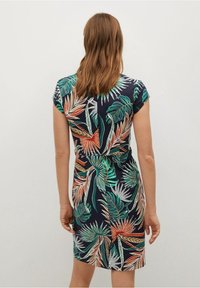 Krátké šaty s krátkými rukávy v tmavě modré barvě s barevným potiskem palmových listů. Mají přiléhavý pas a délku do kolen. Měkká, lehká tkanina.