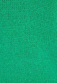 Tessuto a maglia di un vivido verde, caratterizzato da un motivo testurizzato e a coste con punti uniformi, che mostra un colore consistente e un aspetto morbido.