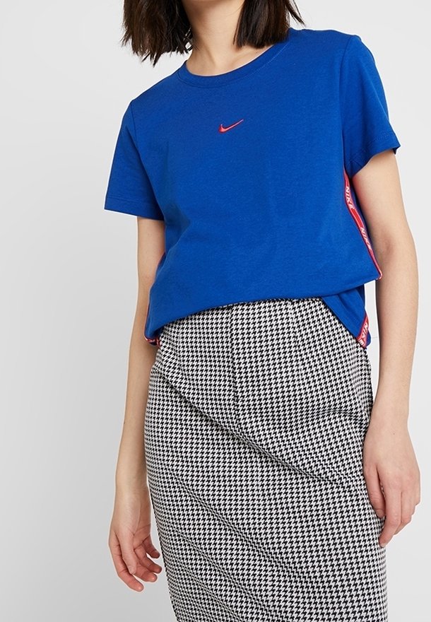 Královsky modré bavlněné tričko s malým červeným logem Nike na hrudi. V kombinaci s tužkovou sukní s kostkovaným vzorem v černé a bílé barvě.
