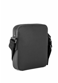 Bolso cruzado negro hecho de tela texturizada. Cuenta con un cierre de cremallera y una correa ajustable, con un diseño minimalista y sin logotipos visibles.