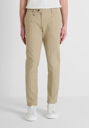 Pantalones beige de corte slim-fit, confeccionados en una mezcla de algodón, con cremallera frontal, dos bolsillos laterales y una textura suave.