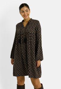Vestido negro y estampado con mangas largas, escote en V y detalles de borlas, que presenta un corsé ajustado y una falda acampanada.