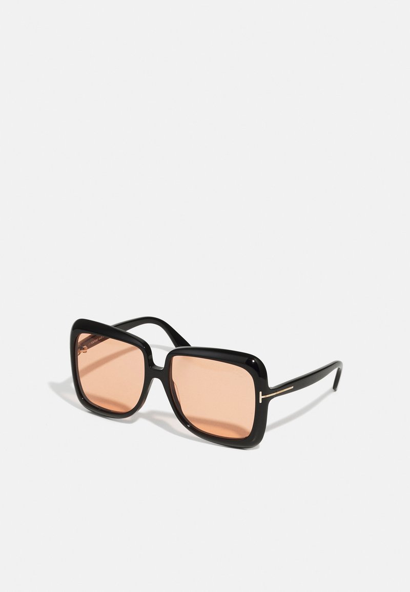 Occhiali da sole oversized neri a forma quadrata con lenti rosa e finitura lucida. Presentano un sottile dettaglio in oro sull'asta.