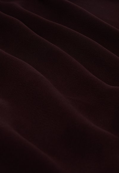Burgundijas audums ar gludu tekstūru, kas parāda mīkstas viļņus un krokas. Izgatavots no viegla materiāla, tam ir dziļa, bagāta krāsa.