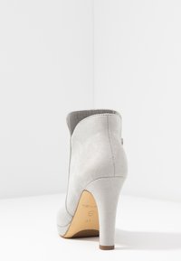 Graue Wildleder-Ankle-Boots mit hohem Absatz, glatter Textur, abgerundeter Spitze und seitlichem Reißverschluss. Mit einem Stiletto-Absatz und einem charakteristischen Logo auf der Sohle.