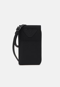 Černá kožená kabelka přes rameno s embosovaným logem, s texturovaným povrchem, obdélníkovým tvarem a nastavitelným popruhem.