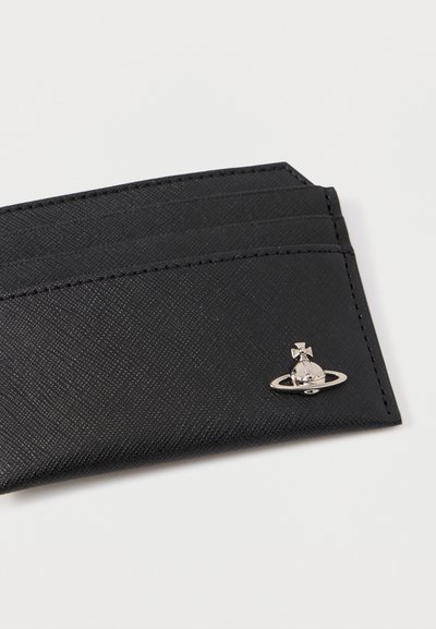 Μαύρος θήκη κάρτας από υλικό με υφή διαθέτει τέσσερις θήκες και μια ασημένια λεπτομέρεια σε σχήμα πλανήτη με ένα σταυρό στην κορυφή.