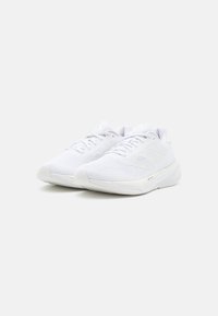 Zapatillas deportivas blancas con parte superior de malla, cierre de cordones, superficie texturizada y suela de goma flexible. Presenta tres franjas en los laterales.