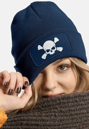 Navy blue knit beanie featuring a white skull and crossbones patch. The texture is ribbed, with a snug fit and flexible material.