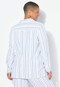 Camicia a maniche lunghe bianca e blu a righe con colletto, chiusura a bottoni, fessure laterali e tessuto testurizzato.