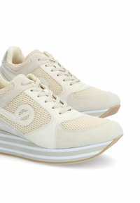 Sneaker beige con materiali in rete e suede, punta rotonda, design con lacci e suola a strati con strisce bianche e marroni chiari.