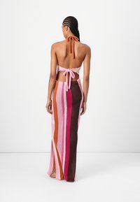 Heklet kjole med halterneck, prydet med vertikale striper i rosa, oransje, brunt og rødt, med åpen rygg og sidesplitt.
