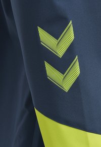 Marina atletiska shorts med en strukturerad gul geometrisk design i ett zickzackmönster, med ett slätt översta tyg och ett gult accentband.