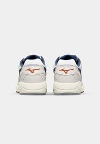 Sportske tenisice s bijelim, mornarsko plavim i sivim odbojnikom, sivi kože kao akcenti i crvena gumena potplat. Zapažena logotipna oznaka na peti.