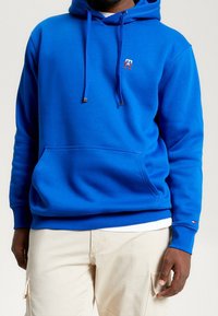 Felpa con cappuccio blu, dotata di tasca frontale, lacci e piccolo logo rosso e bianco. Tessuto morbido, vestibilità comoda, polsini a costine.