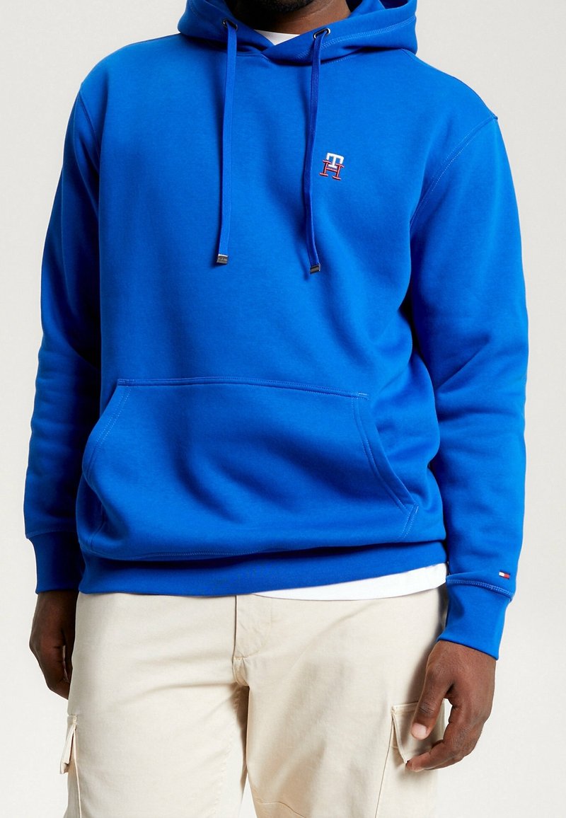 Felpa con cappuccio blu, dotata di tasca frontale, lacci e piccolo logo rosso e bianco. Tessuto morbido, vestibilità comoda, polsini a costine.