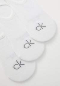Fehér pamut bokazoknik, szürke "ck" logóval. Simább textúra alacsony kivágású kialakítással. Három pár kiállítva.