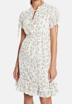 Robe florale avec un fond blanc et des fleurs roses, manches courtes avec liens, taille smockée et ourlet à volants.