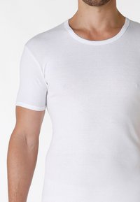 T-shirt bianco a maniche corte realizzato in morbido cotone. Presenta un collo rotondo con rifiniture bianche a contrasto. Texture liscia e leggera.