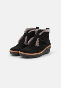 Black suede ankle boots with grey faux fur trim, strap detail, and wedge rubber sole. Features a stitched midsole and textured outsole.