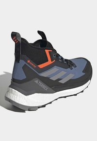 Męskie buty trekkingowe z czarną siateczką, szarymi i pomarańczowymi akcentami, amortyzującą białą podeszwą środkową oraz trwałą gumową podeszwą zewnętrzną.