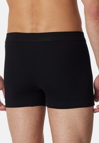Zwarte katoenen boxer shorts met een gladde textuur en een zachte tailleband, met een aansluitend ontwerp en een lengte tot halverwege de dij.