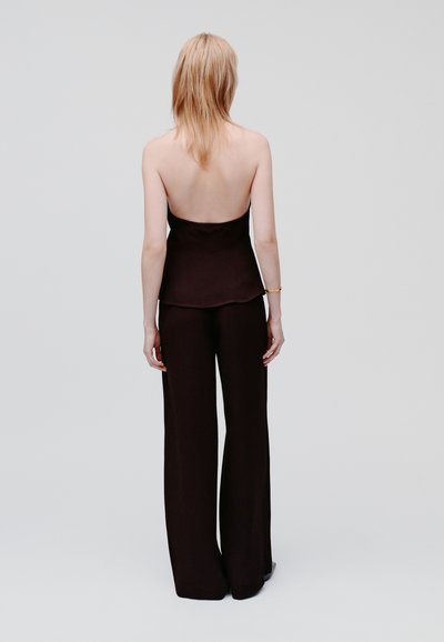 Top nero senza maniche con busto aderente e pantaloni a palazzo in tessuto abbinato. Texture liscia, design minimal e senza embellishments visibili.