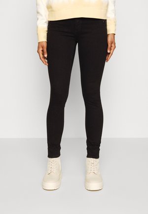 Jeans skinny pretos com uma textura suave e um design ajustado, combinados com botins de plataforma de cor creme com fecho de atacadores.