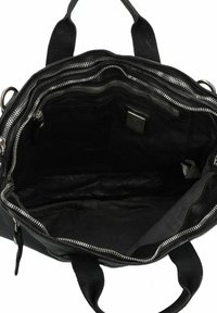 Interior de un bolso de cuero negro que presenta compartimentos con cremallera, textura suave y múltiples bolsillos. Forrado con tela oscura, asas resistentes.