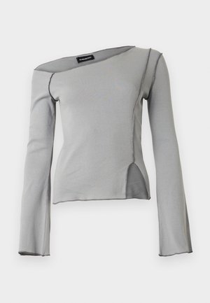 Světlounce šedý top s dlouhým rukávem, asymetrickým výstřihem, viditelnými švy a detailem šikmého rozparku vpředu na boku.