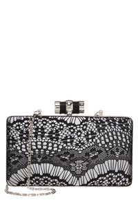 Obdelhová černobílá kabelka s jemným krajkovým vzorem, stříbrný rám, klapka ve tvaru mašle a připevněný stříbrný řetěz.