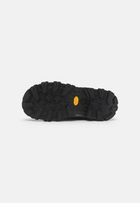 Sort gummisåle med dype mønstre og et distinkt gult Vibram-logo. Robust design egnet for utendørs bruk.