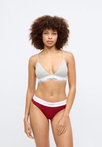 Hallhalline kolm nurka bralette reguleeritavate rihmadega ja valge Calvin Kleini paela; punased ribakujulised hipster-ületised valge vööga.