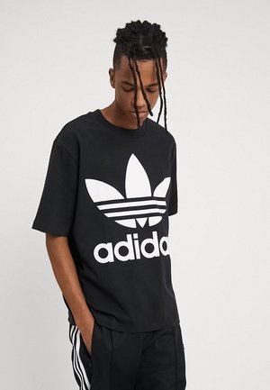 T-shirt in cotone nero con un grande logo bianco Adidas e tre strisce bianche. Maniche corte e design a girocollo.