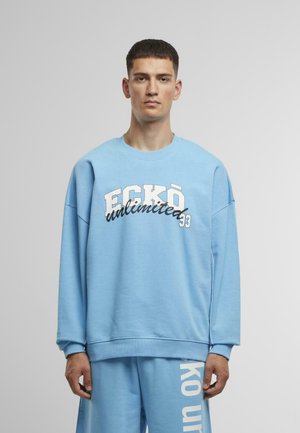 Light blue sweatshirt with oversized fit, featuring "ECKŌ unlimited" in white and black text. Soft fabric with ribbed cuffs and hem.