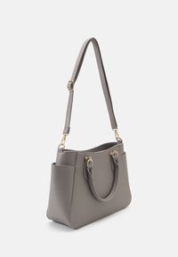 Sac à main structuré gris avec des poignées courtes et une longue bandoulière ajustable, avec des ferrures dorées et des poches latérales.