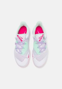 Vita atletiska skor med nätstruktur, mintgröna detaljer och rosa innersulor. Har lavendellöpare och en rosa "Just Do It"-logotyp.