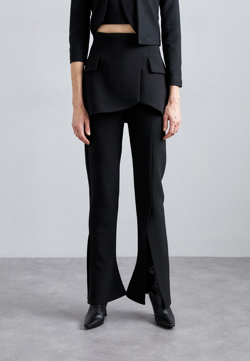 Sorte skræddersyede bukser med et lagdelt fald, to frontlommer og sideslids. Sammen med en cropped top og ankelstøvler.