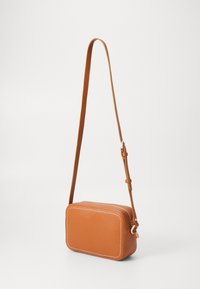 Braune Leder-Crossbody-Tasche mit rechteckiger Form, weißen Nähten, verstellbarem Tragegurt und Reißverschlussdetails in Goldton.