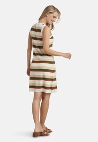 Strickkleid mit horizontalen Streifen in Creme, Olivgrün und Rost. Ärmelloses Design, knielang, mit lockerem Schnitt und strukturiertem Stoff.