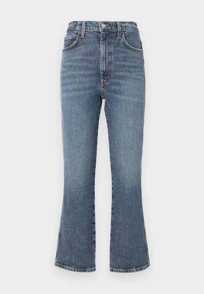 Högmidjade, utsvängda denimjeans i en medelblå tvätt. Har traditionella fickor och en hållbar knäppning. Distressed texturdetalj.