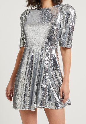 Stříbrné šaty s flitry, krátkými nafouknutými rukávy, kulatým výstřihem a rozšířenou sukní, s celoplošným lesklým efektem.