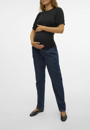Haut de maternité noir à rayures avec des manches courtes bouffantes, associé à un pantalon en denim bleu foncé et des flats noirs, présentant une coupe décontractée.