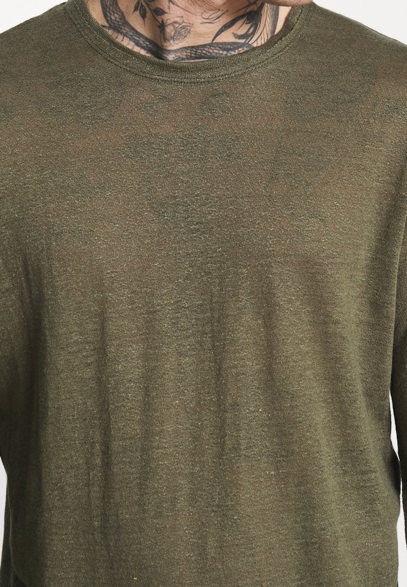Olivegrünes Langarmshirt aus leichtem Stoff, mit rundem Halsausschnitt und leicht durchscheinender Textur. Minimalistisches Design ohne Muster.