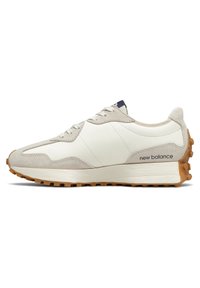 Beige och vit New Balance-sneaker med mockaövertäckningar, gummisula och "new balance"-logotyp på hälen, sedd från den yttre sidan.