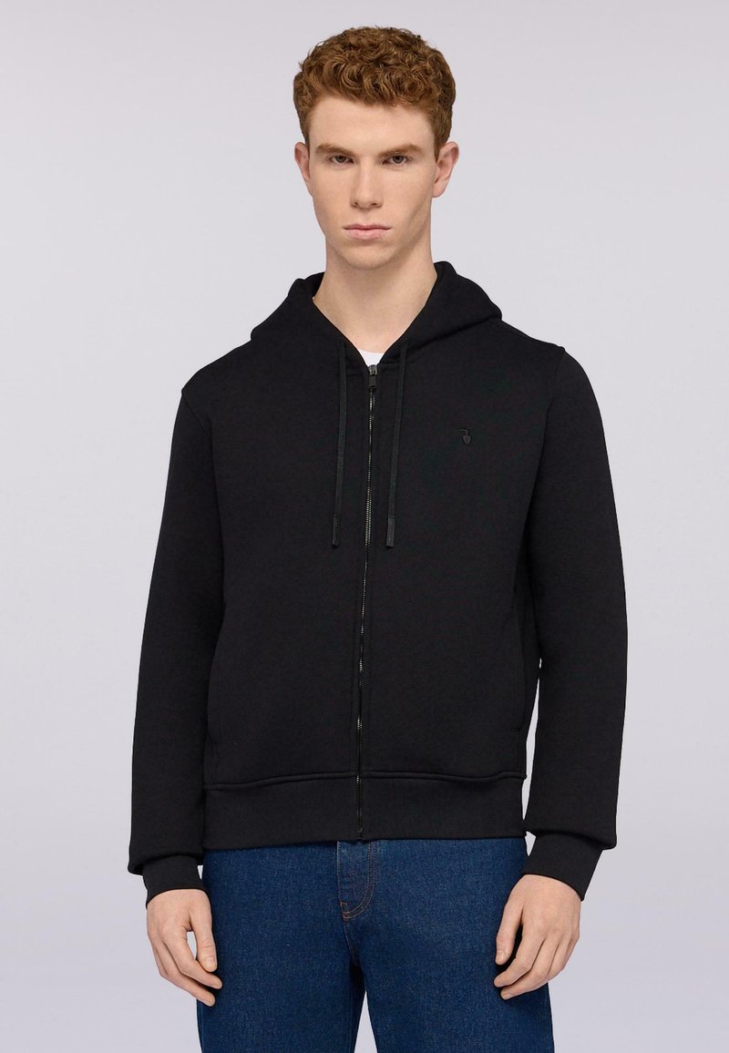Černá mikina na zip vyrobená z hladké tkaniny, s kapucí na šňůrku a předními kapsami, doplněná modrými džíny.