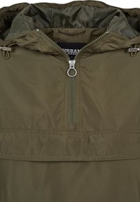 Olivengrønn hettejakke med halv glidelås og ringtrekk, med justerbar snor på hetten og synlig innerfôr.