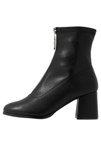 Bottines en cuir noir avec un talon carré, dotées d'une fermeture éclair sur le côté et d'une finition lisse ; design élégant avec un bout pointu.